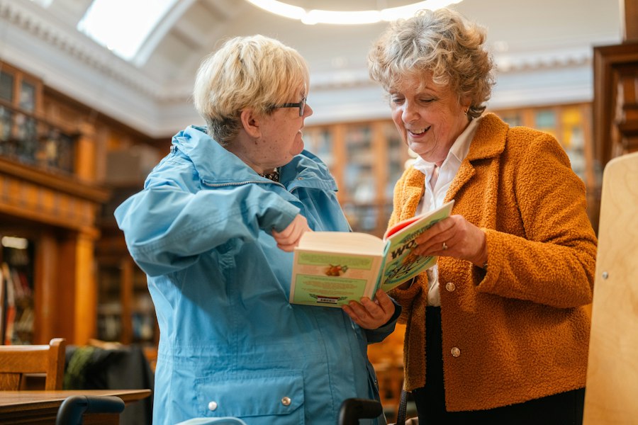 Two women looking through a book together in a library
