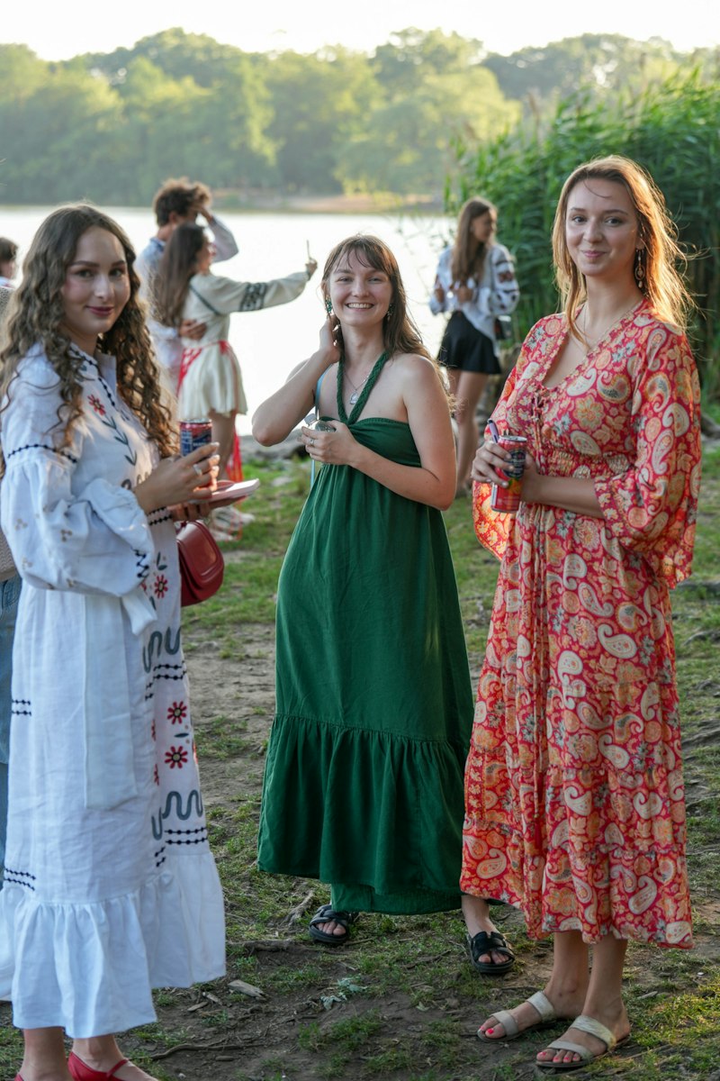 Women in summer dresses at an outdoor gathering by a lake